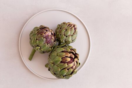 Minimalistic image ofartichokes in a white plate on a light grayの写真素材