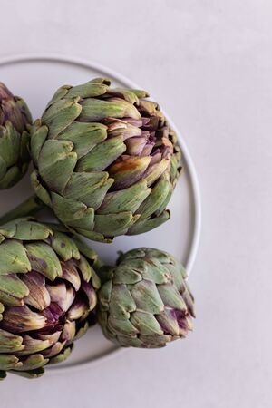 Topview image of artichokes in a white plate over light gray bacの写真素材