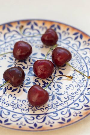 Cherries on a white plate with dark blue ornamentの写真素材