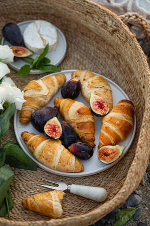 Upper view shot of a delicious breakfast with croissants and figs served with cheese in a woven basket.の写真素材