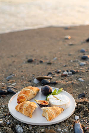 Vertical image of the beach picnic with figs, croissants and camamber cheese. Negative space.の写真素材