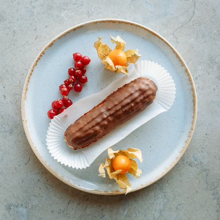 Eclair in chocolate with berries
