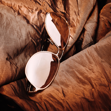 sunglasses on brown shiny fabricの写真素材
