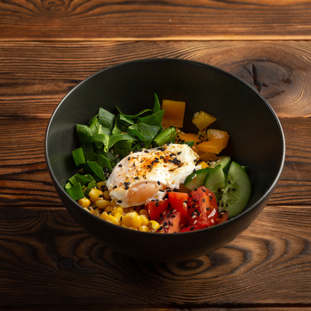 vegetable poke in black plate on wooden backgroundの写真素材
