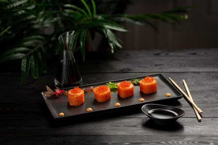 Sushi rolls set with tuna on a black rectangular plate on a black wooden backgroundの写真素材