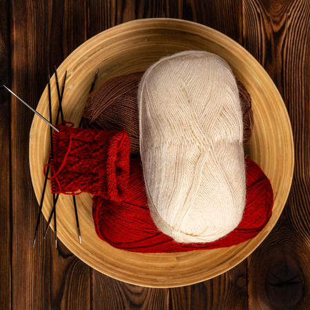 colored balls of thread and knitting needles with a knitting on a wooden backgroundの写真素材