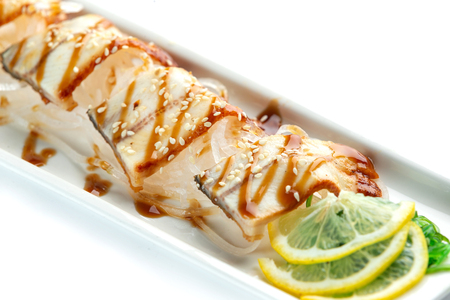 pieces of white fish with lemon and herbs on a rectangular plate on an isolated white backgroundの写真素材