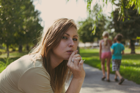 beautiful girl with flowing hair chewing a blade of grass against the background of a summer streetの写真素材
