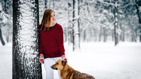 a beautiful girl in a Burgundy sweater and white pants stands leaning against a tree near the Red...
