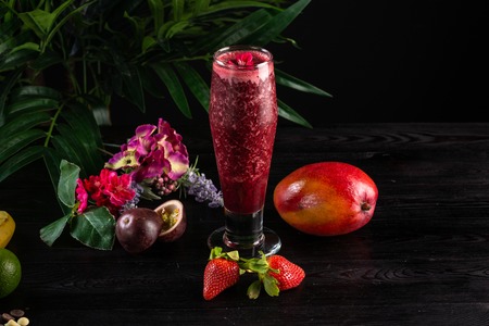 Cocktail with fruits and berries in a tall glass on a dark wooden backgroundの写真素材