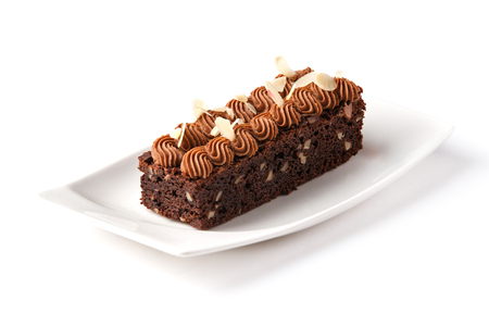 brownie decorated with chocolate cream and almond flakes in a white rectangular plate on an isolated white backgroundの写真素材