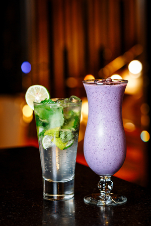 cocktails on the table - mojito and berry smoothie in a glasses on a legの写真素材