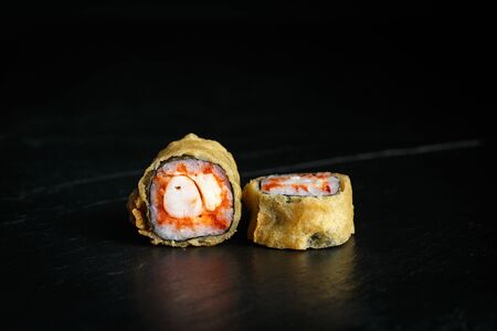 pair of sushi rolls tempura ebi itame with krab close-up on a dark backgroundの写真素材