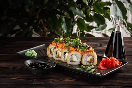 sushi roll set on a round plate and soy sauce on a dark wooden backgroundの写真素材