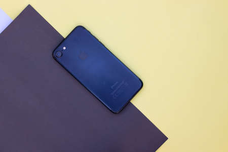 An smart-phone on a yellow and black colored paper background.