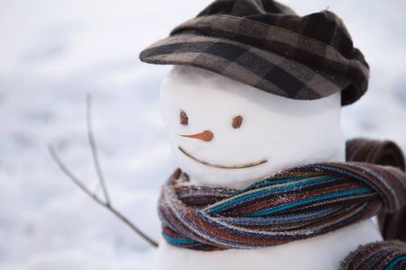 Snowman in brown peaked cap and scarf