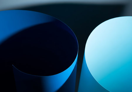 A close-up, abstract view of two curved pieces of paper, one deep blue and the other a bright cyan, creating a sense of depth and movement with dramatic lighting and shadows.の素材