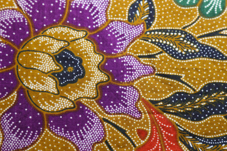 An antique retro batik fabric with an ochre background adorned with a Dali-esque oriental purple and white floral pattern.