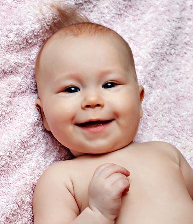 Newborn smiling baby on the pink blanketの写真素材