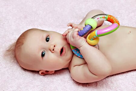 Newborn baby with colorfull rattle on th blanketの写真素材
