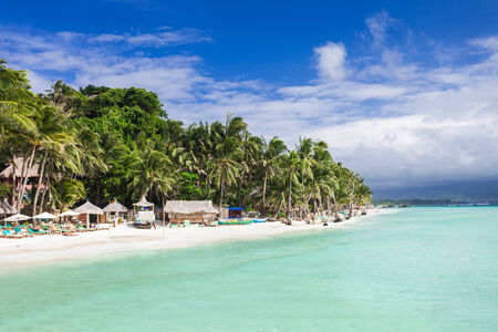 Beauty beach with coconut palms on the blue sky background