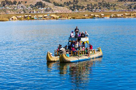 PUNO, PERU - MAY 14, 2015: Unidentified tourists in Totora boat, Titicaca lake near Puno, Peru