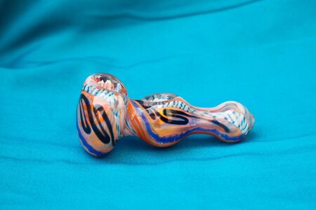 Glass pipe or bong for marijuana smoking on a blue fabric backgroundの写真素材