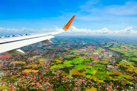 MANILA, PHILIPPINES - FEBRUARY 23, 2013: Cebu Pacific airplane wing above the Manila city suburbs in Philippinesのeditorial素材