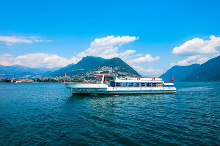 Tourist boat in Lugano lake and Lugano city in canton of Ticino in Switzerlandの写真素材