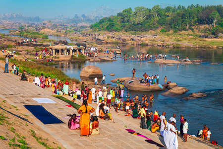 HAMPI, INDIA - FEBRUARY 20, 2012: Indian people bathing and washing their clothes in the river in Indiaのeditorial素材