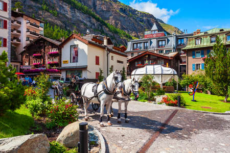 ZERMATT, SWITZERLAND - JULY 15, 2019: Horse coach and traditional local houses in the centre of Zermatt town in the Valais canton of Switzerlandのeditorial素材