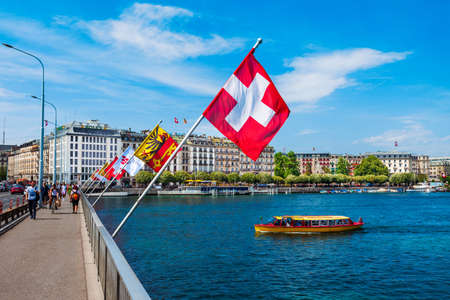 GENEVA, SWITZERLAND - JULY 20, 2019: Swiss flags at the Pont du Mont Blanc bridge in Geneva city in...