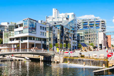 OSLO, NORWAY - JULY 20, 2017: Bridge through canal at the Aker Brygge neighbourhood in Oslo, Norway....