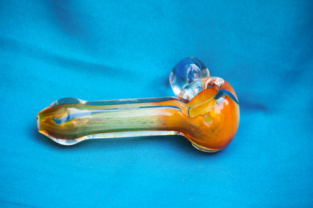 Glass pipe or bong for marijuana smoking on a blue fabric backgroundの写真素材