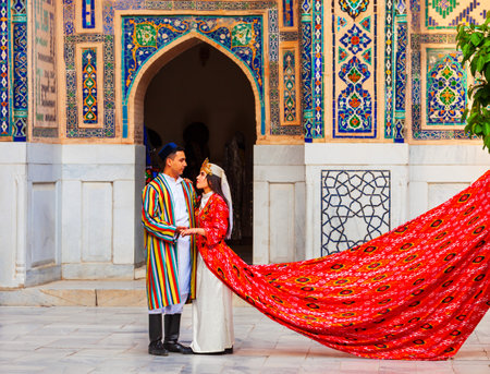 Samarkand, Uzbekistan - April 18, 2021: Bride and groom in traditional uzbek dresses at Registan ancient city, Samarkand city in Uzbekistanのeditorial素材