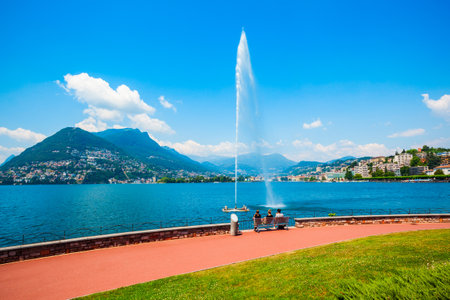 Fountain at Lugano lake and Lugano city panoramic view in canton of Ticino in Switzerlandの写真素材
