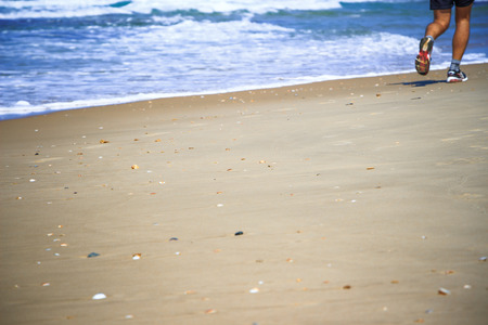 feet of the man running along the seashoreの写真素材