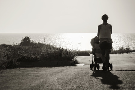 stretching into the distance to the sea mother with stroller. black and white photoの写真素材