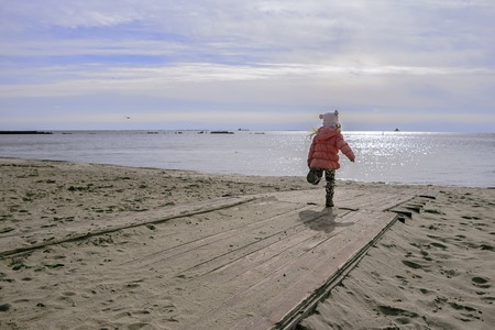 Little gerl running on wooden deck to the beachの写真素材