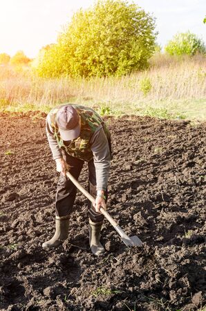 The farmer plows the land with a shovelの写真素材