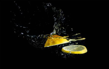 Splashing lemon in water on black backgroundの写真素材
