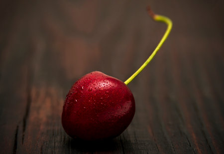 Cherries in low key lighting on dark wood backgroundの写真素材