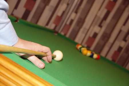 Man hand with a cue is plaing billiard
