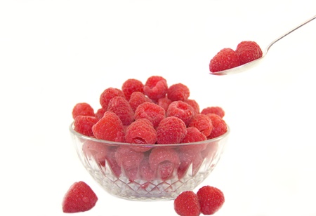 Sweet raspberries in a plate with a spoon isolated on white backgroundの写真素材