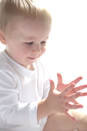 Little boy is clapping his hands on white background