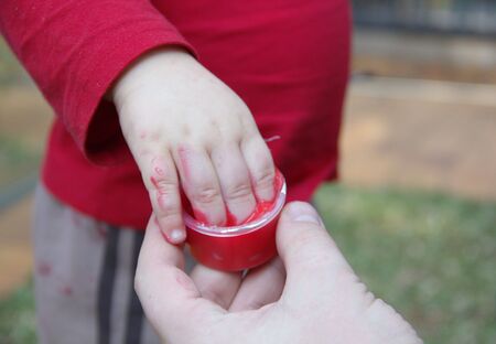 Little fingers of toddler boy in the tube with paint