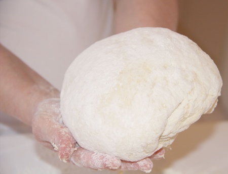 Chef is holding the dough in hands