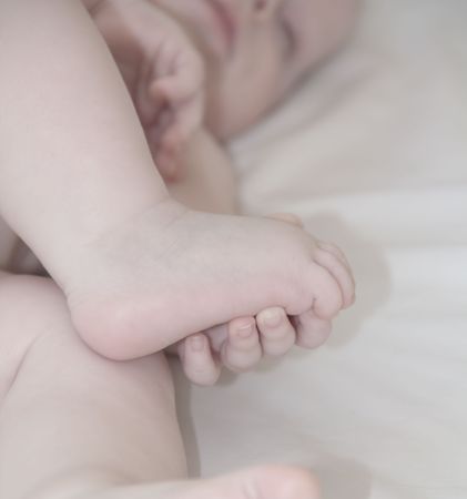 Hand of sleeping baby is holding her footの写真素材