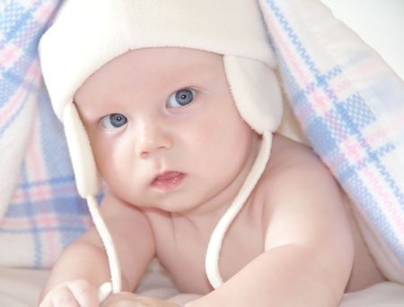 Portrait of beautiful baby under warm checkered blanketの写真素材