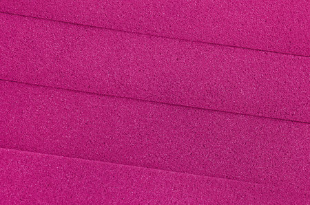 texture background of foam sponge material in pink color with striped surface. pile of thick...